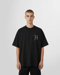 Model wearing the Black T-shirt with initial print in white on the front by Not Guilty Homme