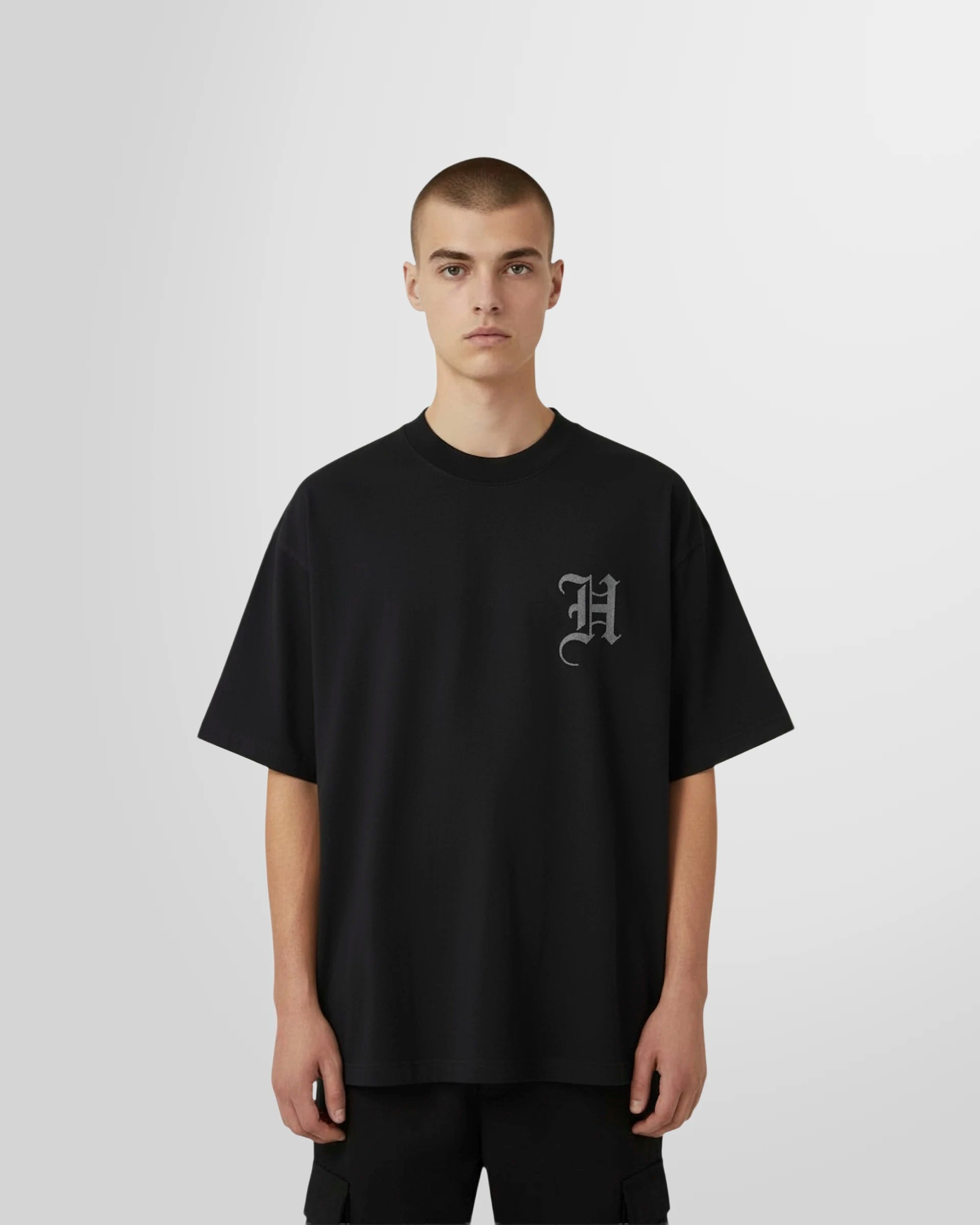 Model wearing the Black T-shirt with initial print in white on the front by Not Guilty Homme