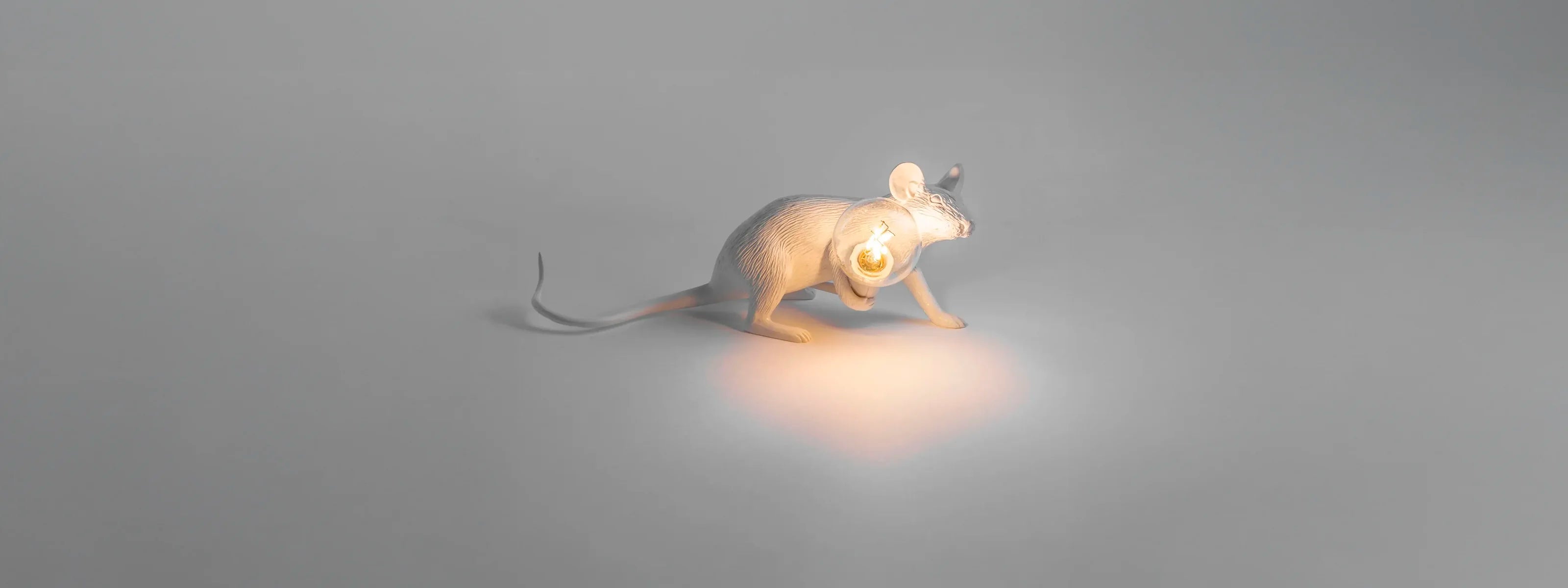 The iconic Seletti Mouse Lamp by Marcantonio, featured as a new arrival at Homme+, sitting on a surface and casting a warm glow.