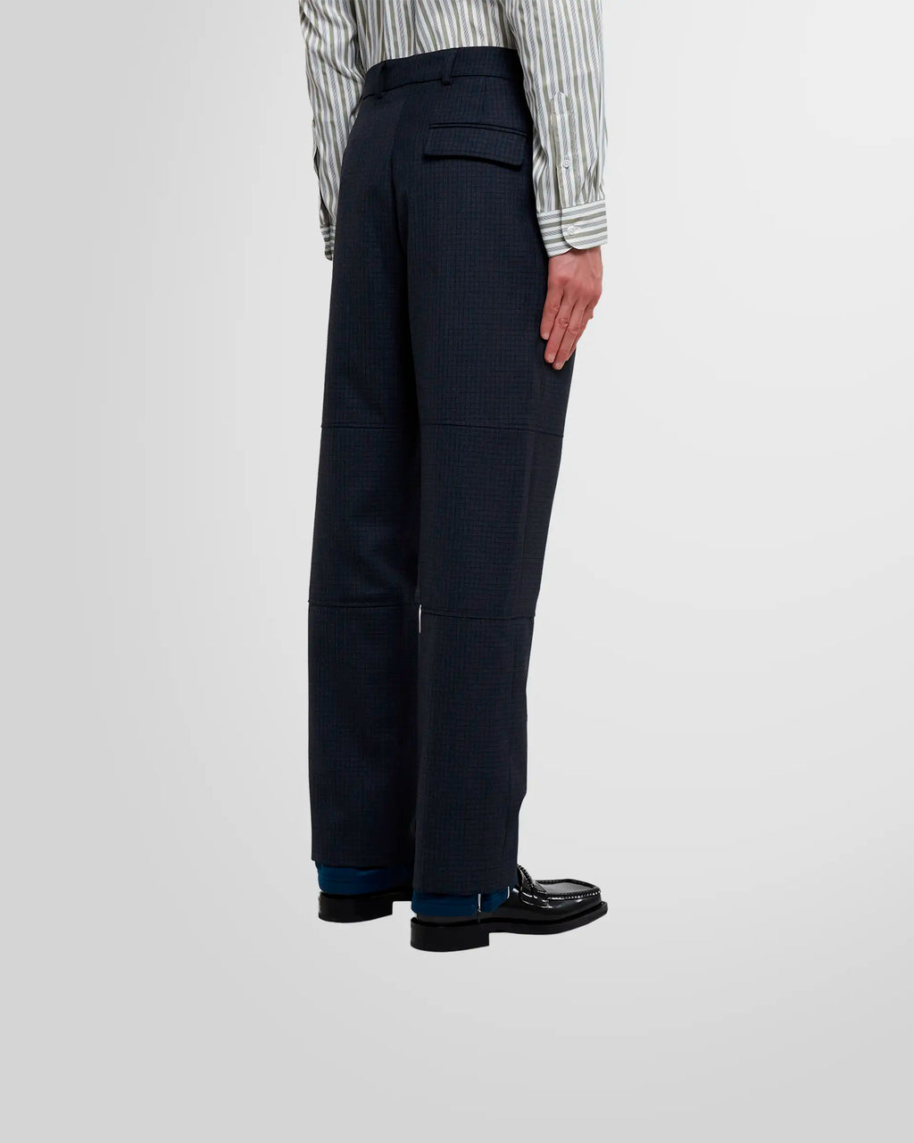 Model wearing Martine Rose Sports Hem Trousers in navy check from a back/side view.