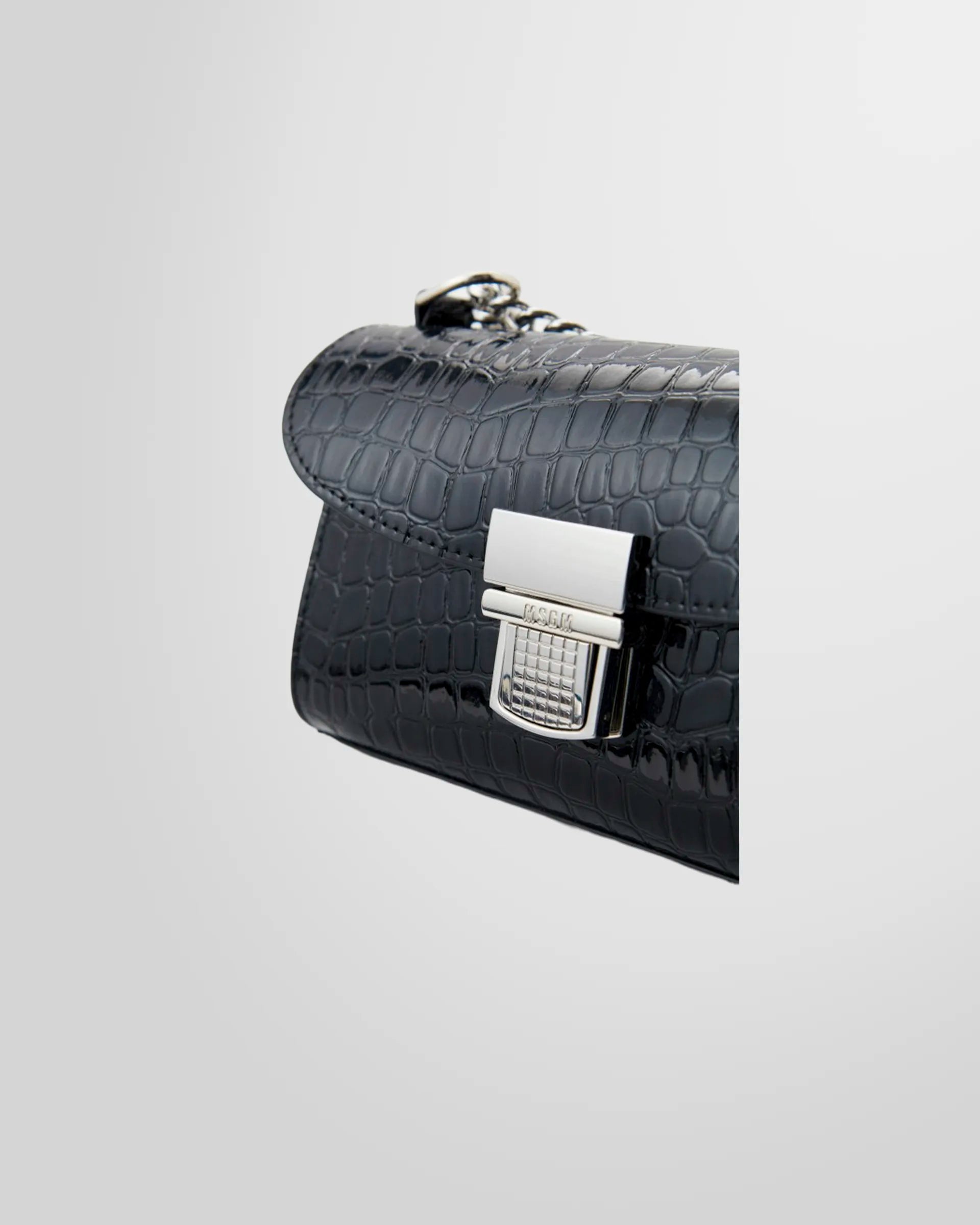 Side profile of the MSGM Black Croc-Embossed Cross-body Bag showing the flap and buckle.