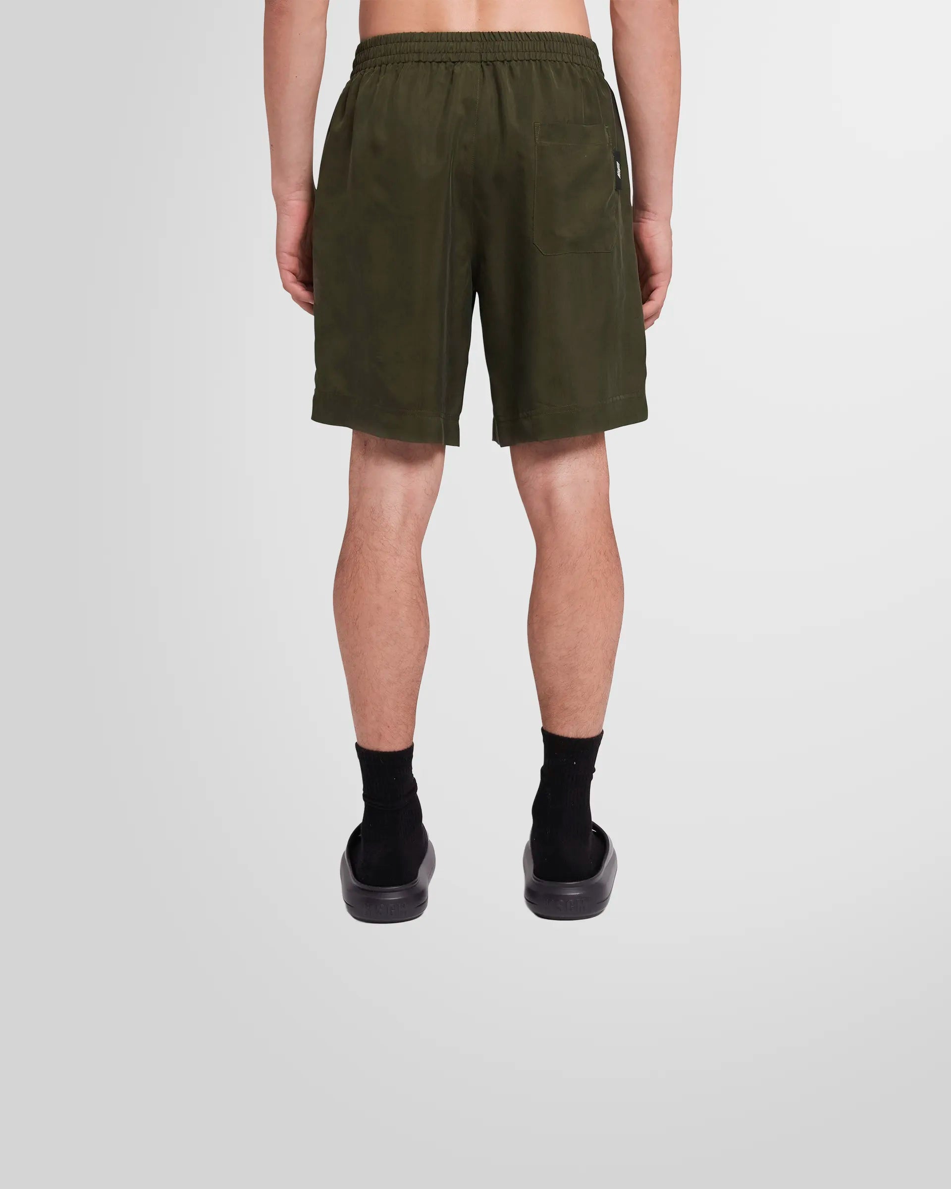 Back view of a model wearing the MSGM Cupro Shorts in military green.