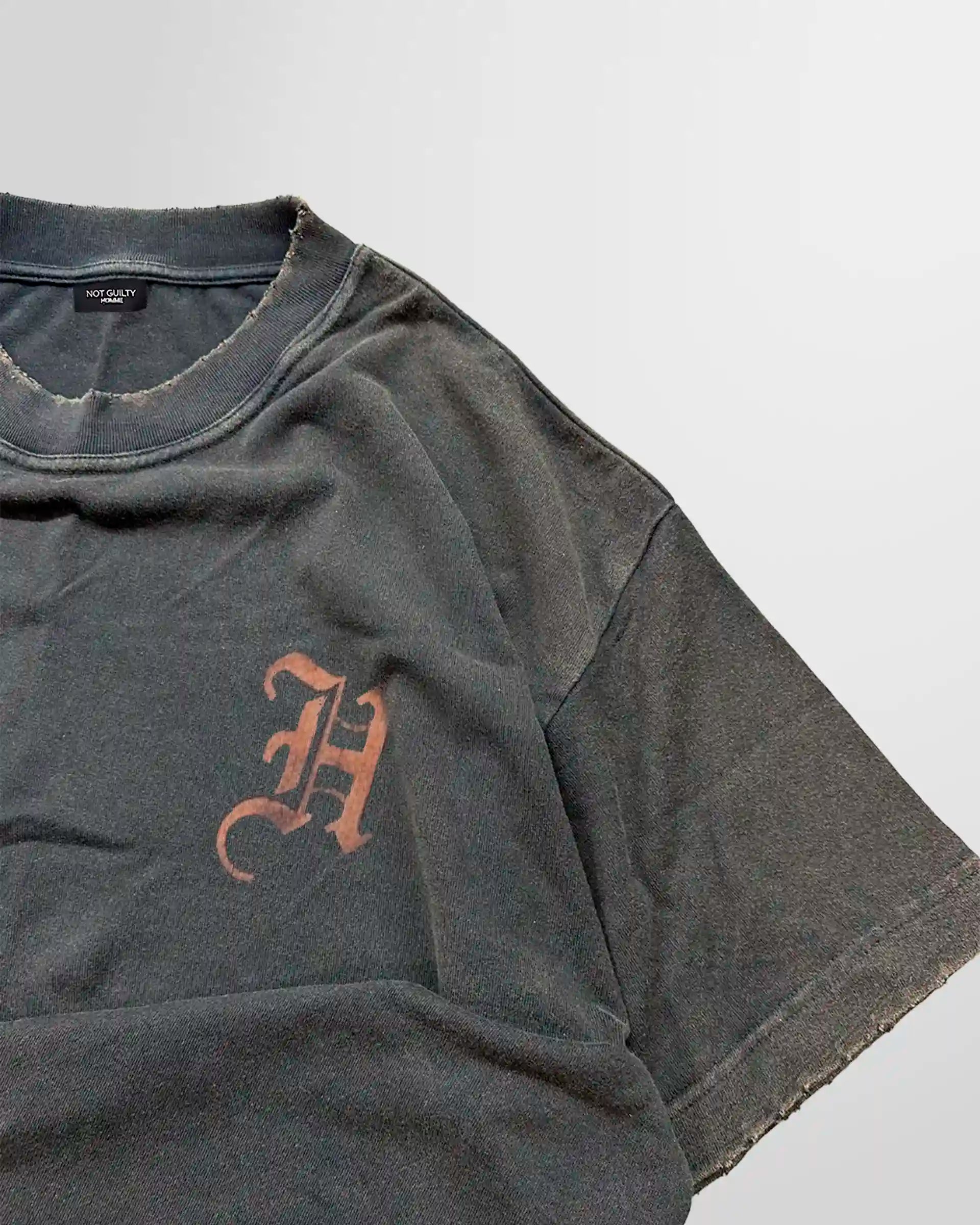 Close‑up of the chest initial print on the acid‑wash t‑shirt.