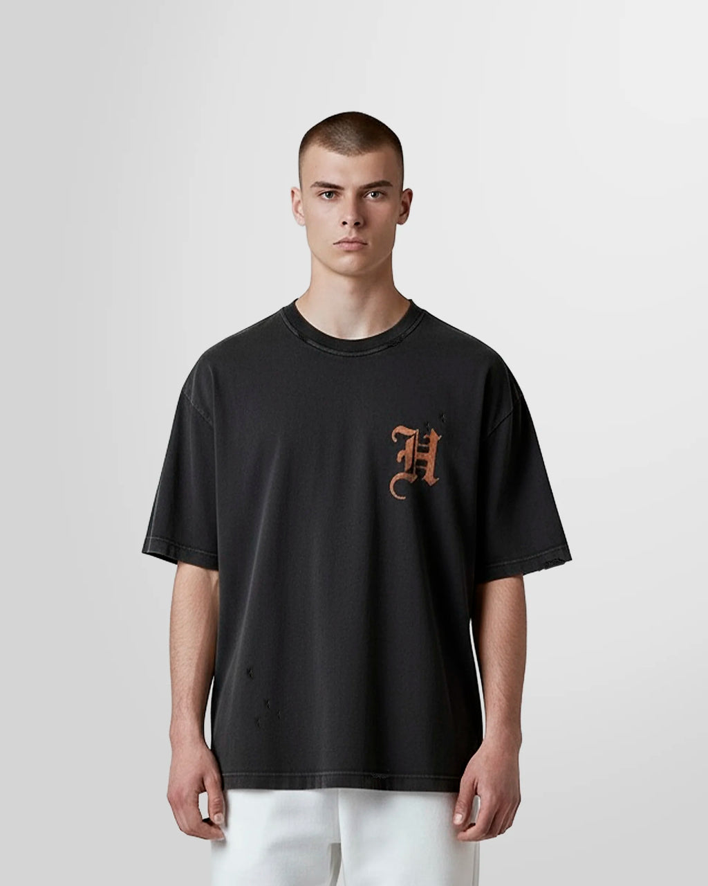 Model wearing the Not Guilty Homme Burn Acid Wash Initial T‑Shirt in distressed black with chest initial print.