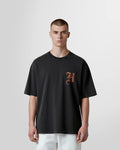Model wearing the Not Guilty Homme Burn Acid Wash Initial T‑Shirt in distressed black with chest initial print.