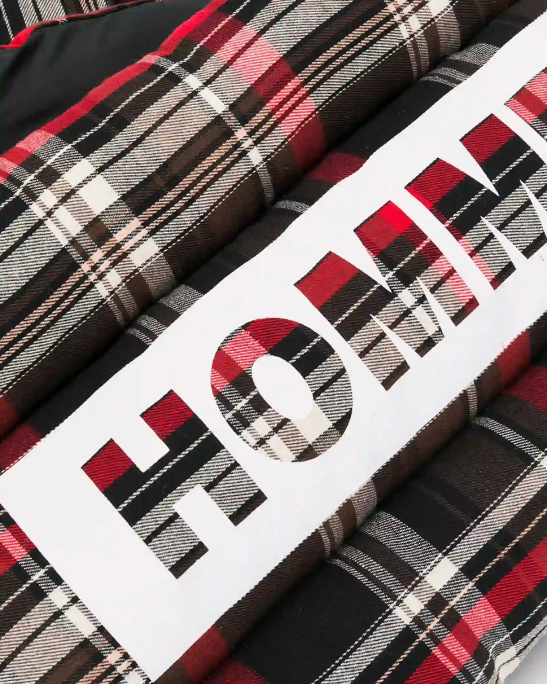 Close‑up of the Not Guilty Homme logo printed on plaid.