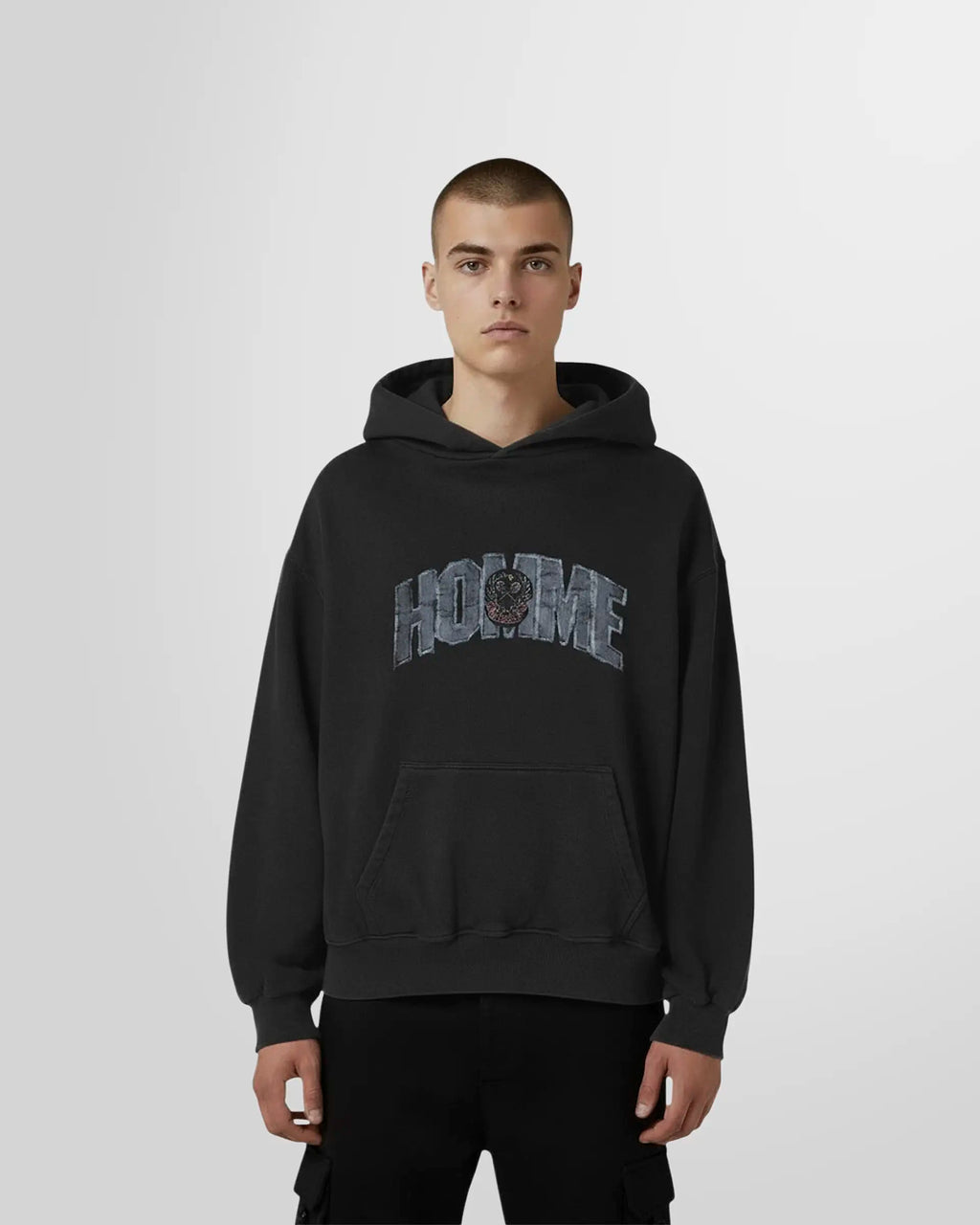 Front view of a model wearing the Not Guilty Homme College Hoodie in black with varsity HOMME graphic in front.