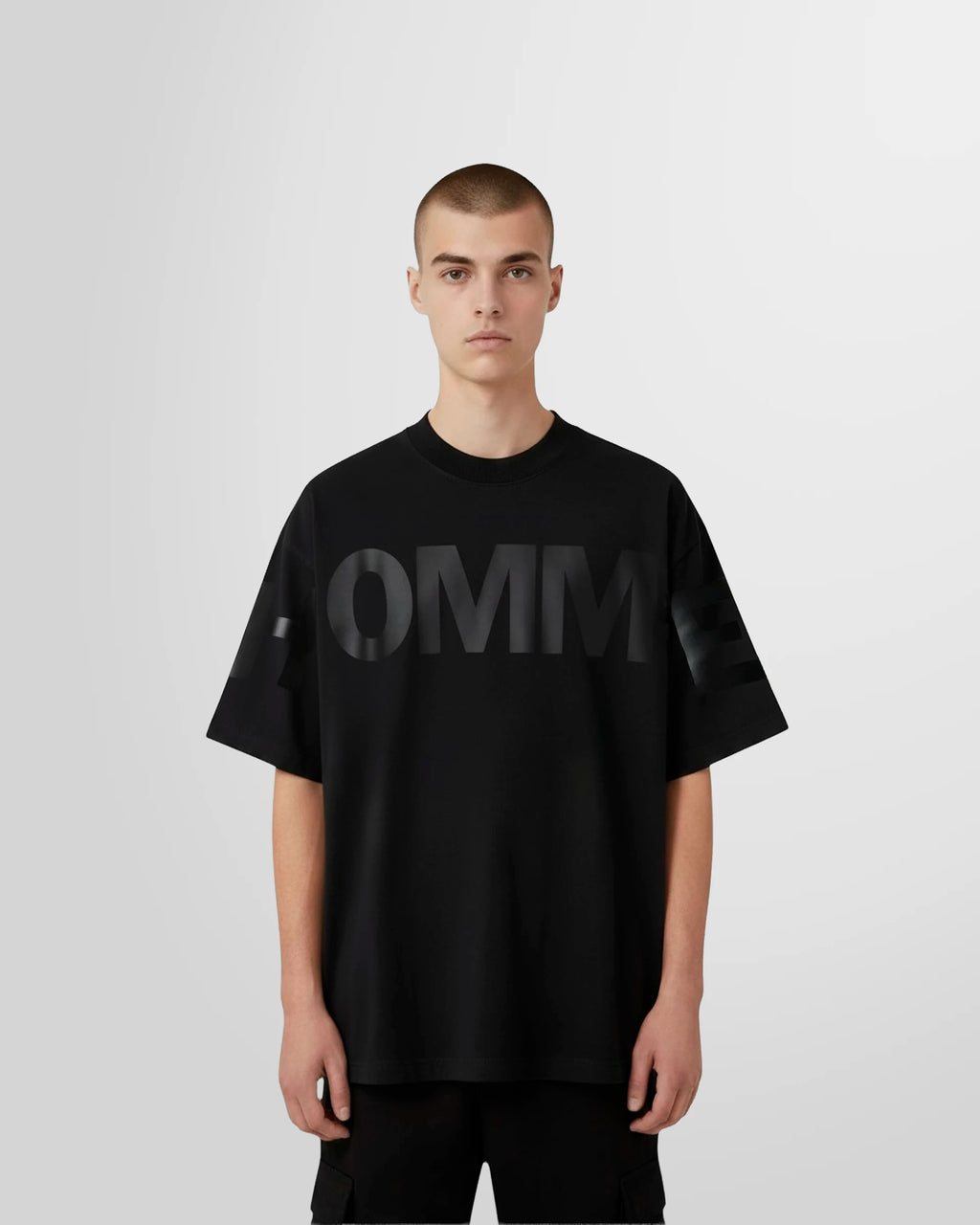 Model wearing the Not Guilty Homme graphic t-shirt in black, showcasing the tonal 'HOMME' print.