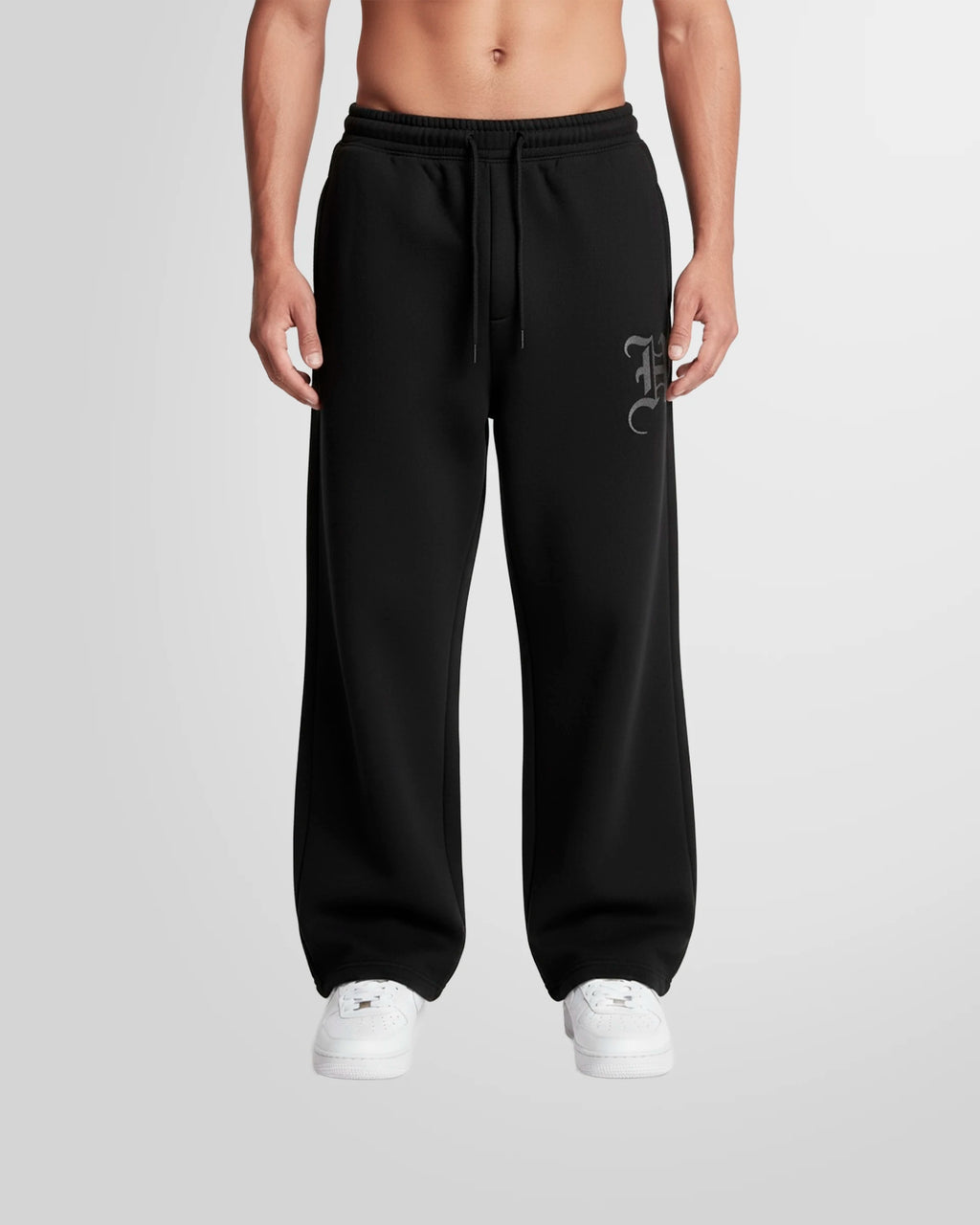 Model wearing the Not Guilty Homme Initial Printed Jogging Trousers in black with thigh initial print.