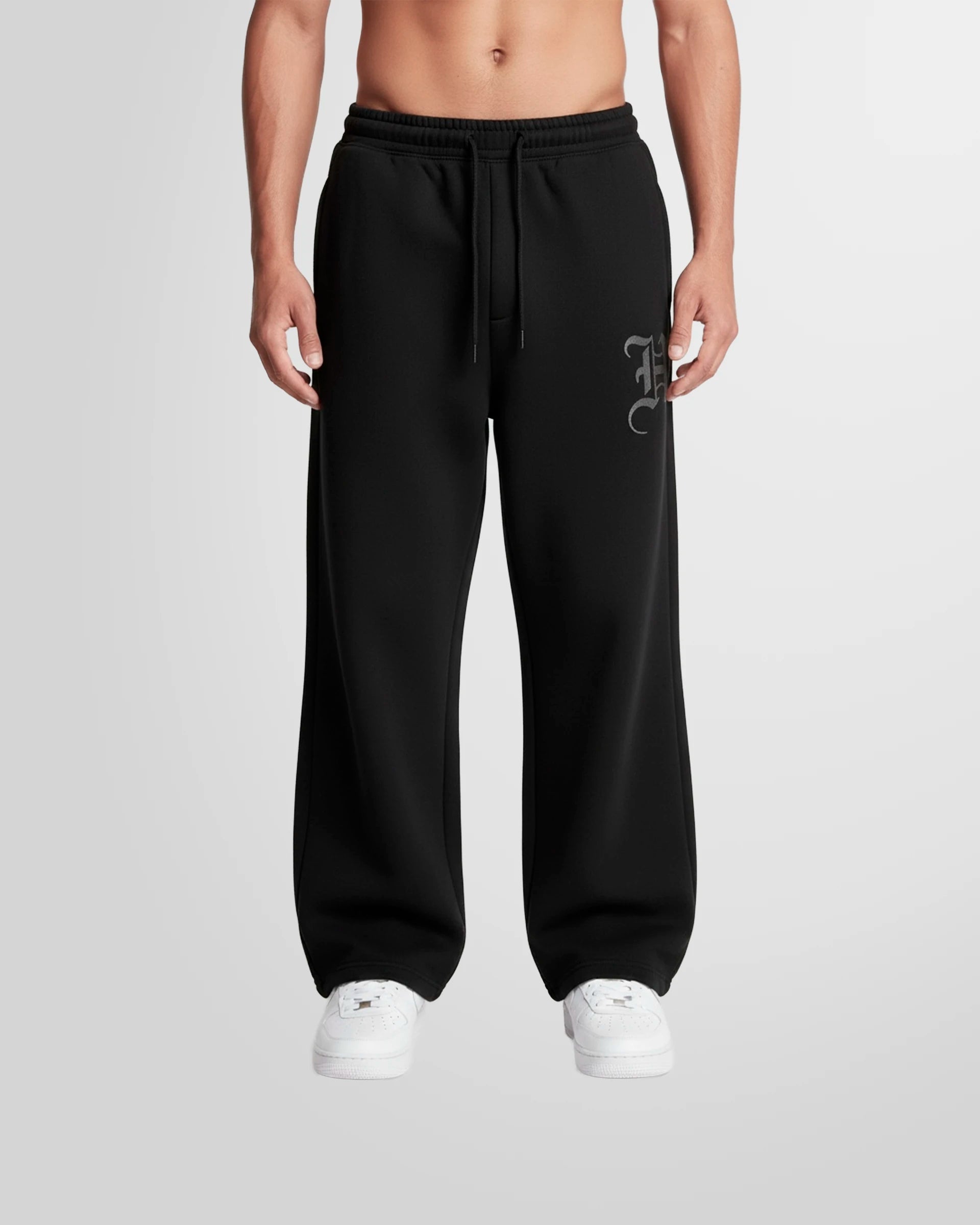 Model wearing the Not Guilty Homme Initial Printed Jogging Trousers in black with thigh initial print.
