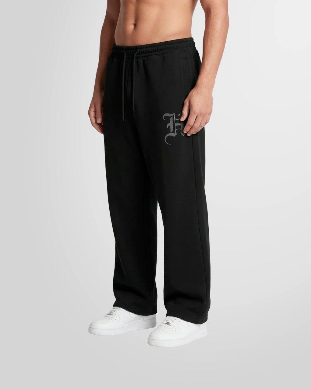 Side view of a model wearing the Not Guilty Homme Initial Printed Jogging Trousers in black with thigh initial print.