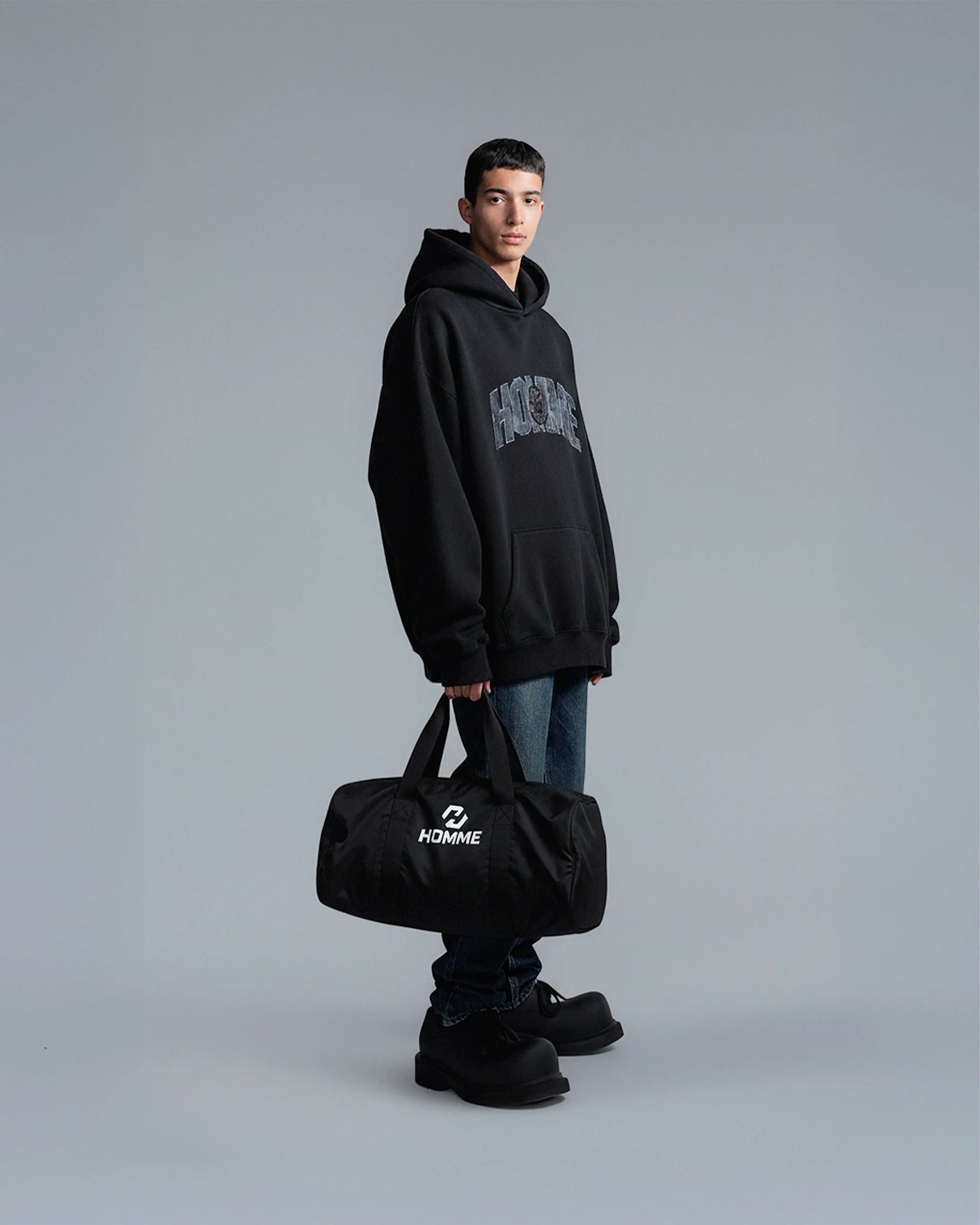 Model carrying the Not Guilty Homme sport bag, demonstrating its scale and function as a modern gym accessory in black.