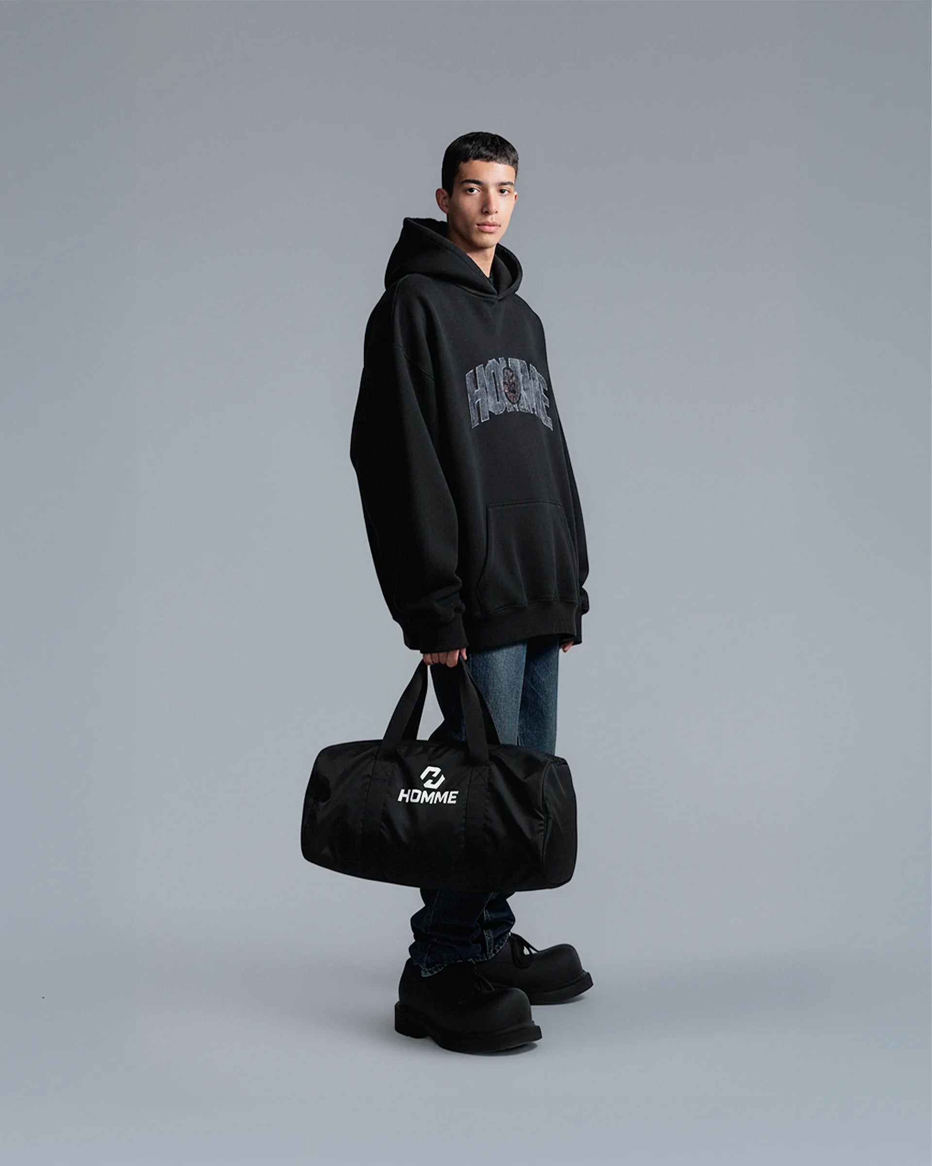 Model carrying the Not Guilty Homme sport bag, demonstrating its scale and function as a modern gym accessory in black.