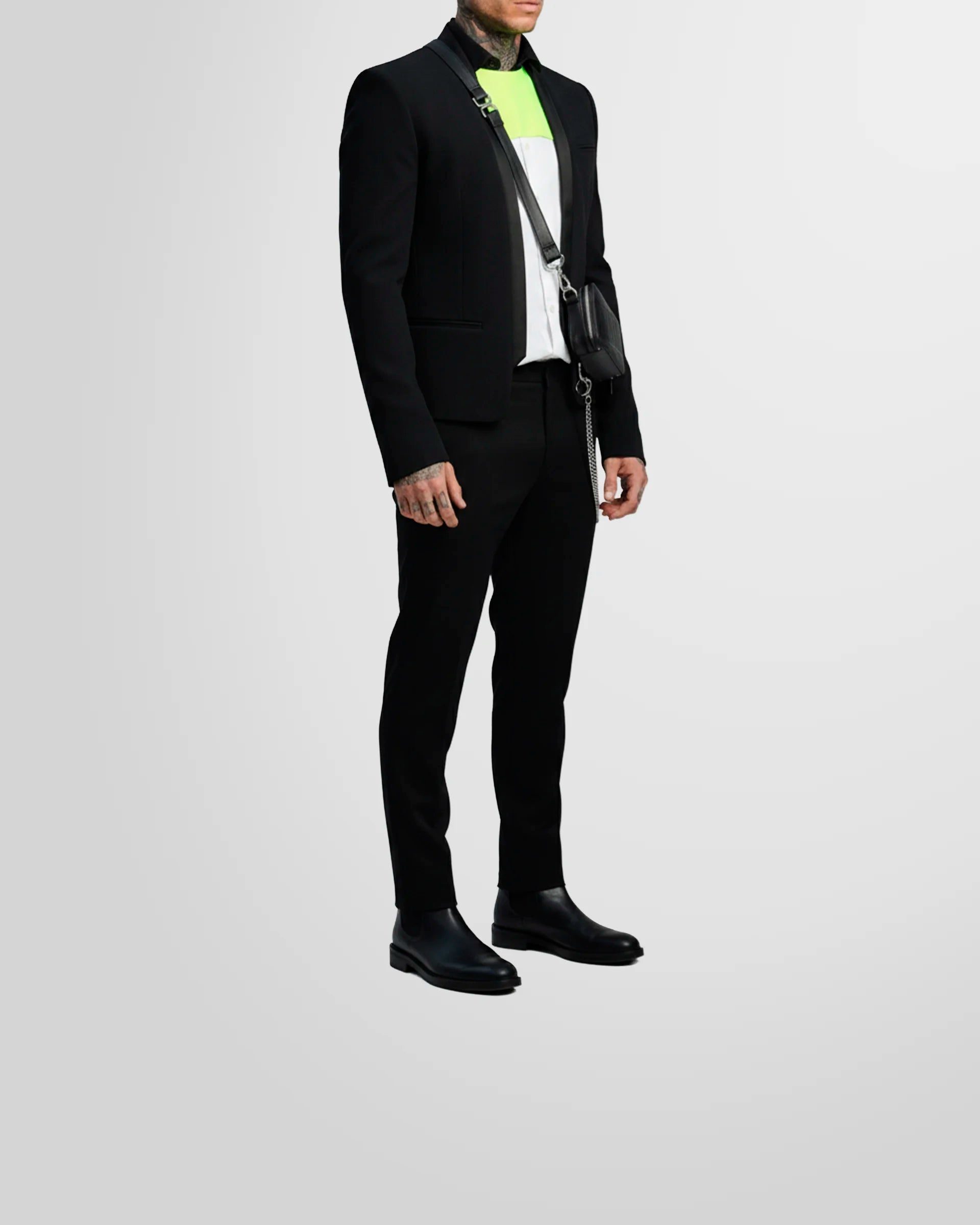 View from the side of a model wearing the Not Guilty Homme blazer, showcasing its straight fit, cropped length, and open-front styling.