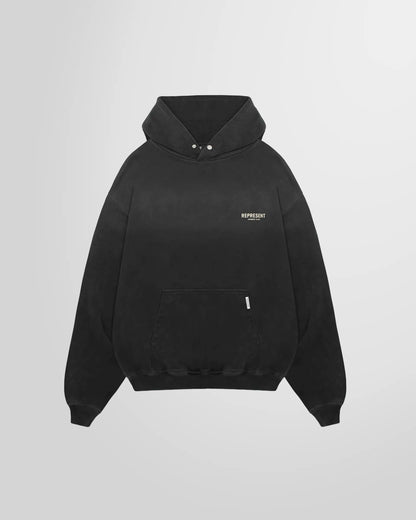 Front view of the Represent Owners' Club Hoodie in aged black, showing the chest print and kangaroo pocket.