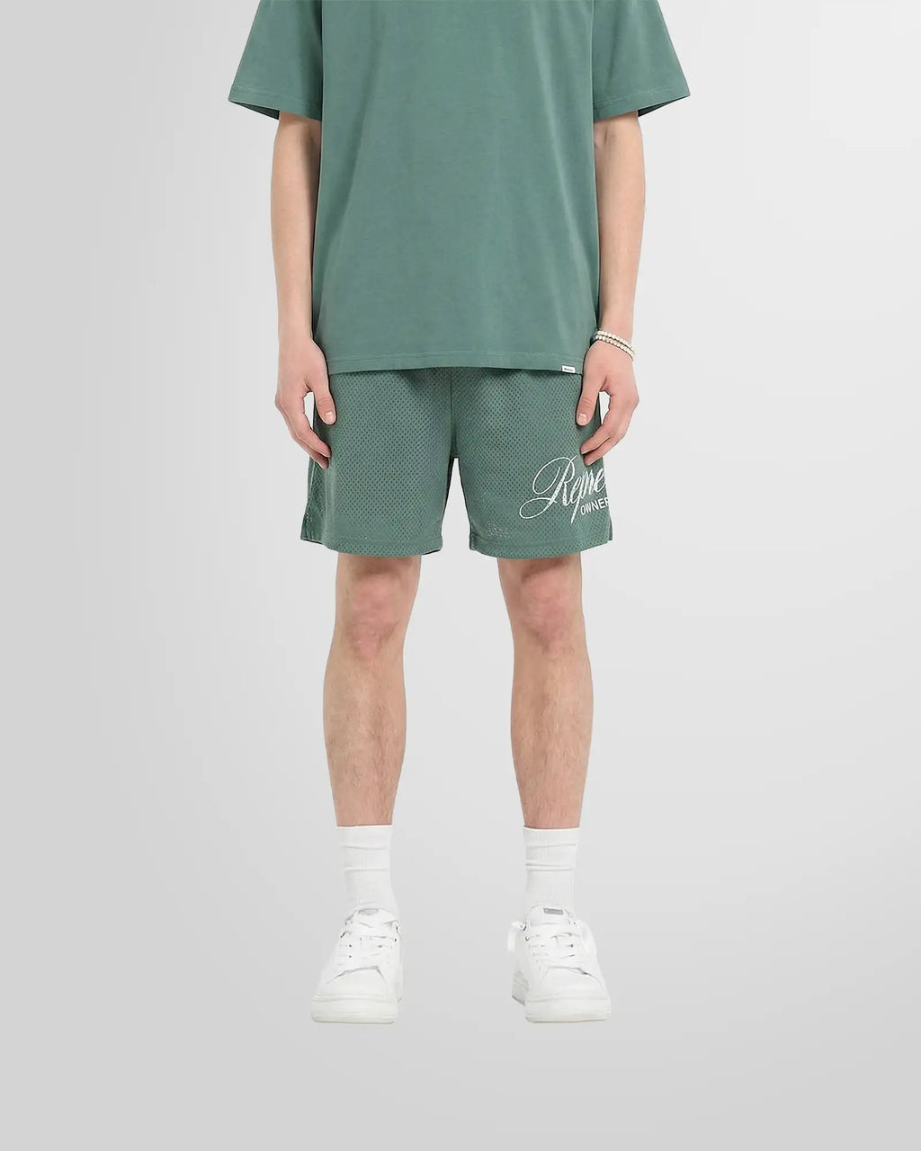 Front view of a model wearing the Represent Owners’ Club Script Mesh Shorts in Vintage Green.