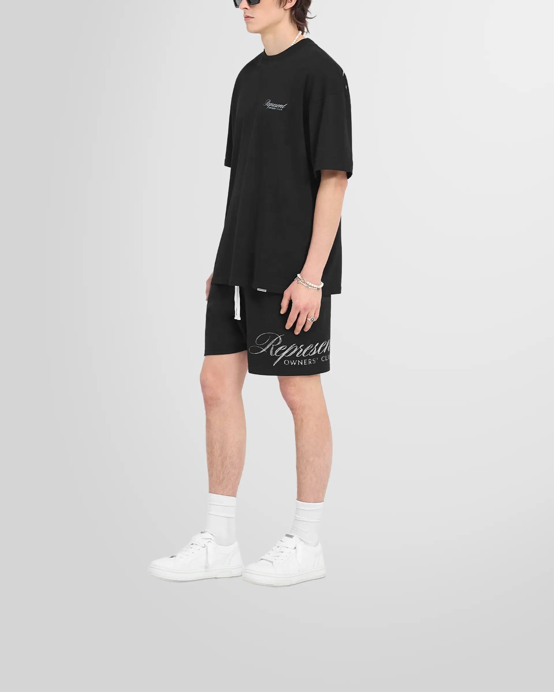 Model wearing the oversized Represent Owners Club Script T-Shirt in black.