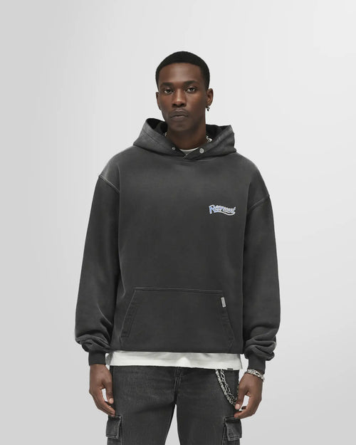 Front view of a model wearing the Represent Showcasing Hoodie in Stained Black with chest script and boxy fit.