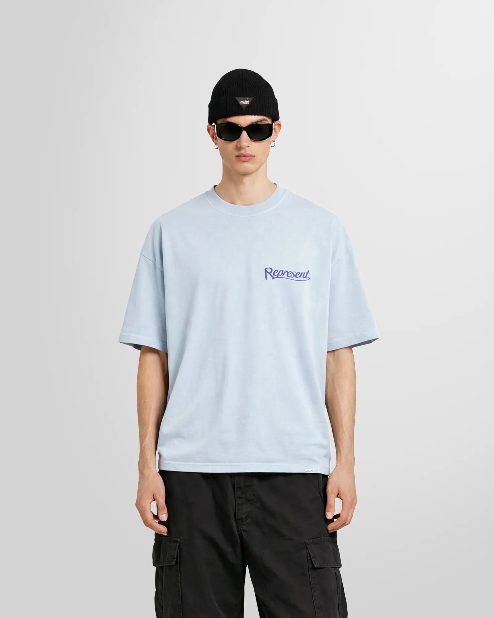 Model wearing the Represent Showcasing T‑Shirt in Cloud blue with small script logo at chest.