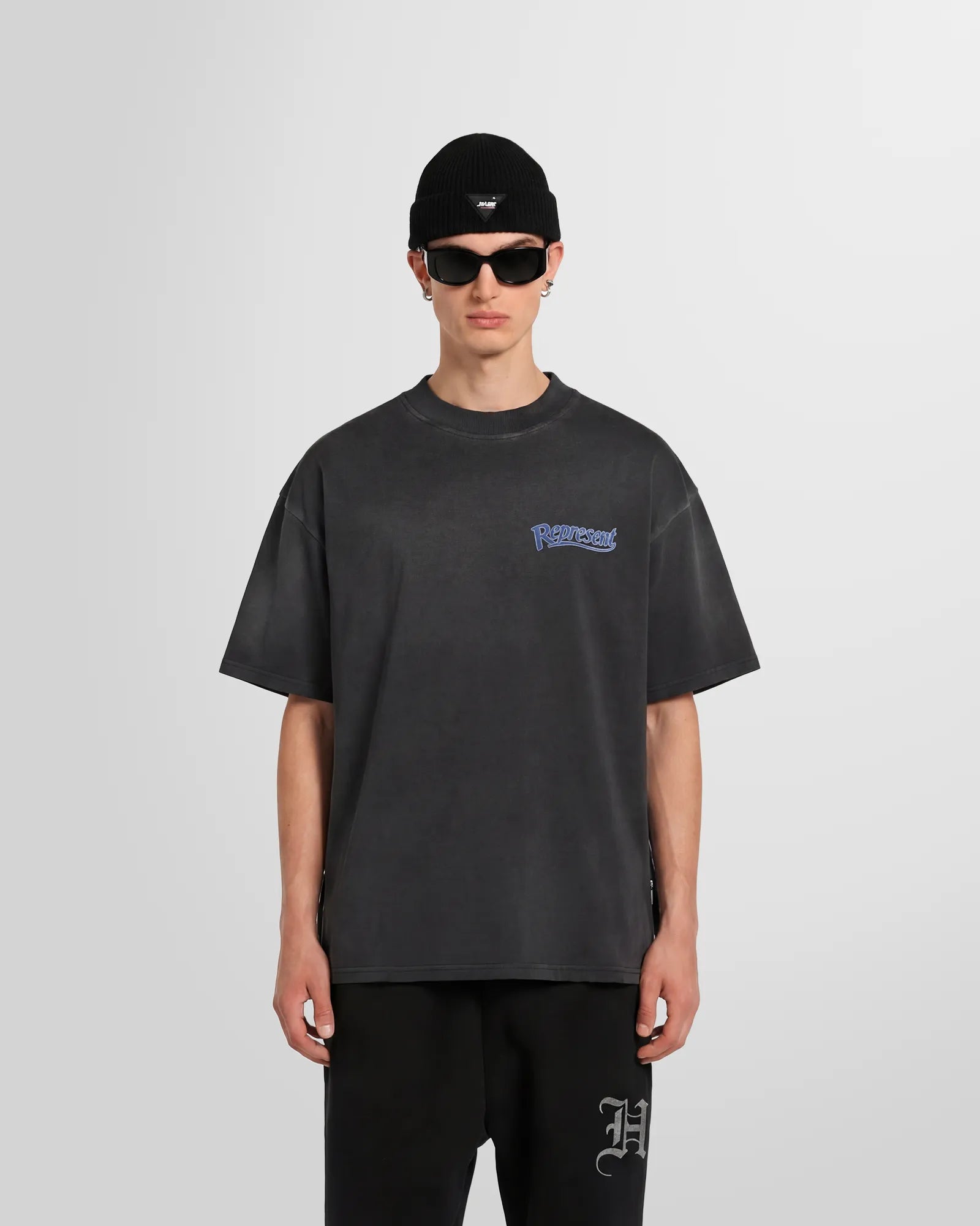 Model wearing the Represent Showcasing T‑Shirt in Stained Black showing the boxy fit and the script logo print.