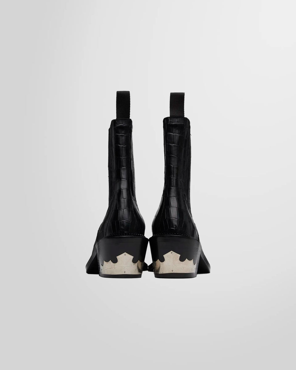 Back view of the boots and the ornate silver-tone Western hardware on the heel of the Toga Virilis black Chelsea boots.